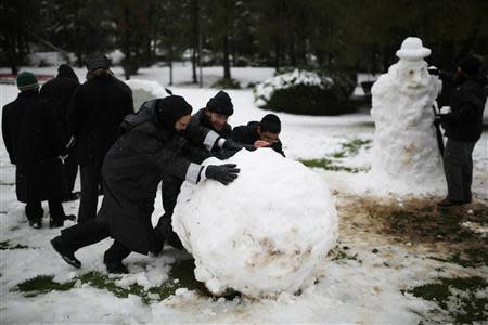 Ultra-Orthodox Jewish men roll a snowball after a snowstorm at a park during winter in Jerusalem December 12, 2013. REUTERS/Amir Cohen