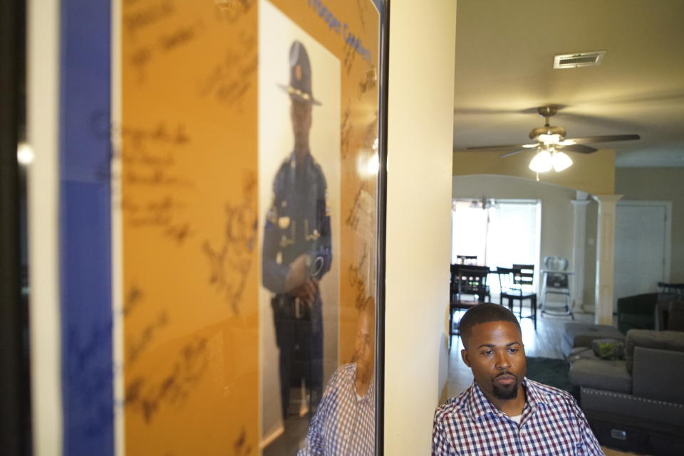 Former Louisiana State Police Trooper Carl Cavalier stands next to a poster he received when he graduated from the state police academy in 2015, at his home in Houma, La. on Friday, Oct. 15, 2021. Cavalier, who went through the same class with Jacob Brown, described him as “untouchable.” “A select few cadets in the academy carried themselves with a certain swagger, a vibe that said they were sure they’d make it through,” Cavalier said. “They didn’t have any doubts.” (AP Photo/Allen G. Breed)