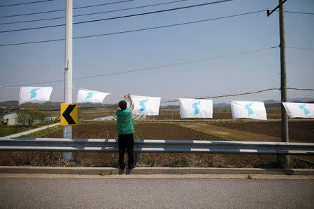 FILE PHOTO: A man hangs a unification flag on the Grand Unification Bridge which leads to the Peace House, the venue for the inter-Korean summit, near the demilitarized zone separating the two Koreas in Paju, South Korea, April 25, 2018. REUTERS/Kim Hong-Ji