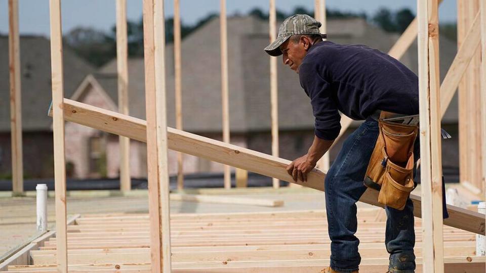 High demand is stoking inflation in building materials like lumber, which is up more than fourfold from a year ago. A carpenter aligns a beam for a wall frame at a new house site.