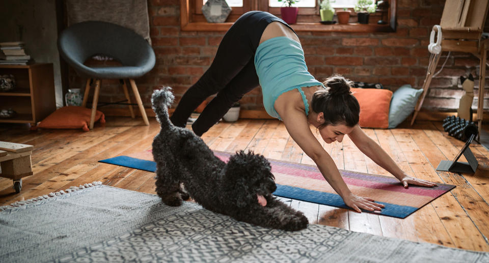 Woman does yoga with her dog.