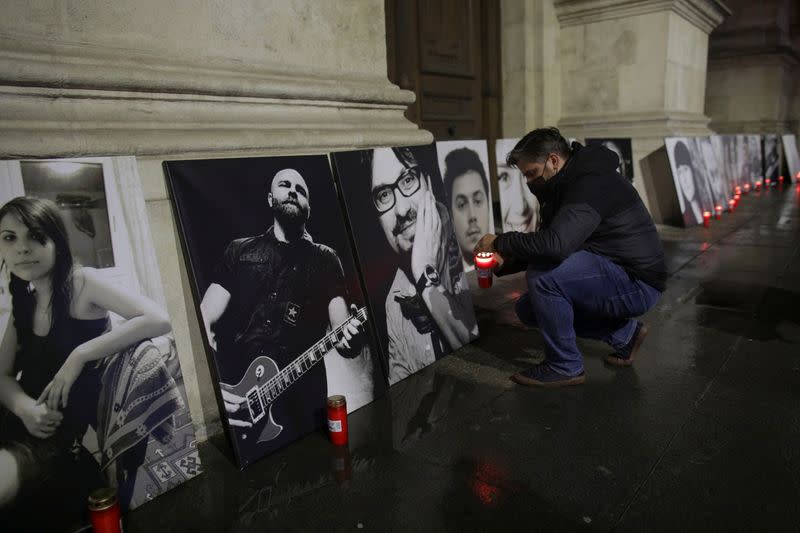 Activist Marian Raduna lights a candle in front a portrati of one of the victims of the Colectiv fire,