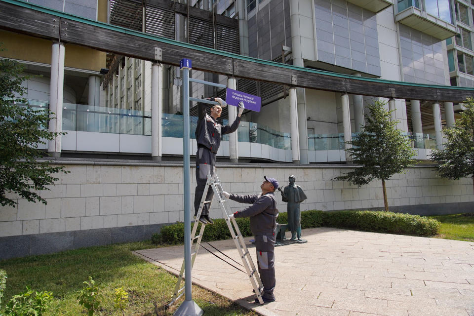 Municipal workers adjust a sign reading "Luhansk People's Republic Square" outside the British embassy in Moscow, Russia, Friday, July 8, 2022. Moscow Mayor Sergei Sobyanin signed the decree naming the stretch outside the embassy after the Luhansk People's Republic.(Alexander Avilov, Moscow News Agency photo via AP)