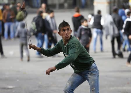 A Palestinian protester uses a sling to hurl stones at Israeli troops following a protest demanding Israel return the bodies of Palestinians who allegedly stabbed Israelis, in the West Bank city of Hebron November 4, 2015. REUTERS/Mussa Qawasma