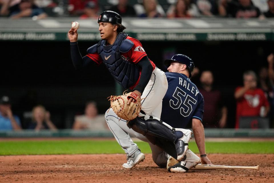 Cleveland Guardians catcher Bo Naylor, left, shows the ball to the umpire after tagging out Tampa Bay Rays' Luke Raley (55) at home plate in the 10th inning Saturday in Cleveland.