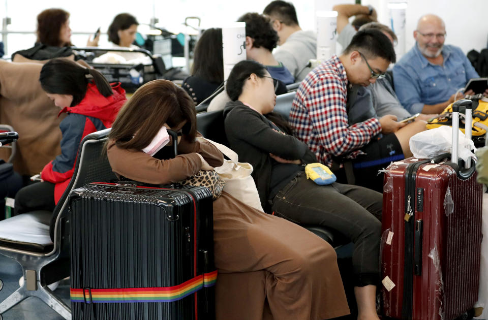 Passengers rest as their flights were cancelled because of Typhoon Hagibis, at Haneda Airport in Tokyo, Saturday, Oct. 12, 2019. Tokyo and surrounding areas braced for a powerful typhoon forecast as the worst in six decades, with streets and trains stations unusually quiet Saturday as rain poured over the city. (Kyodo News via AP)