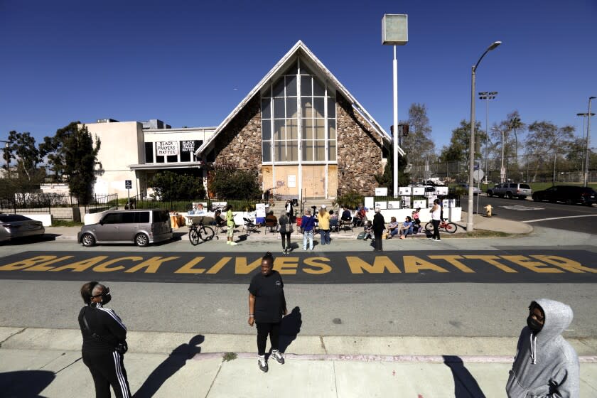 VENICE, CA - FEBRUARY 19, 2022 - - Teresa Smith, from, left, Laddie Williams and her grandson Roy Davidson, Jr., with the Save Venice community organization, gather to celebrate 117 years of contributions made by African Americans to the Oakwood historic community in front of the First Baptist Church of Venice in Venice on Saturday, February 19, 2022. Laddie Williams, 61, center, foreground, sat on the steps of the church every Sunday since 2017 to prevent the church from being torn down. For the past four years Save Venice spearheaded the movement to save the First Baptist Church of Venice (FBCV) resulting in the unanimous vote by the Los Angeles City Council, to approve the motion by Councilman Mike Bonin, to designate the Church as a Historic Cultural Monument. The First Baptist Church of Venice is one of the last remaining significant resources associated with the history and development of Oakwood, an early African American neighborhood in Los Angeles. The mid-century style church was designed by architect George R. Williams in 1910. (Genaro Molina / Los Angeles Times)