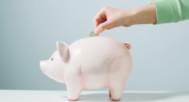 Hand placing coin in piggy bank