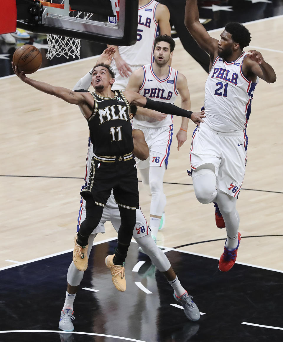 Atlanta Hawks guard Trae Young (11) draws a foul from Philadelphia 76ers center Joel Embiid (21) in the final minute of Game 4 of a second-round NBA basketball playoff series on Monday, June 14, 2021, in Atlanta. (Curtis Compton/Atlanta Journal-Constitution via AP)