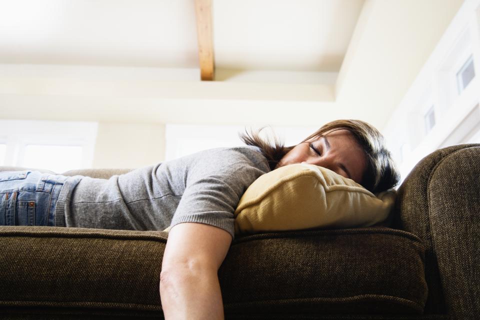 exhausted woman napping face down on a couch