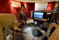 A Singapore Airlines (SIA) stewardess stands next to a display of the new Singapore Airlines First Class seat during their next generation cabin product launch in Singapore on July 9, 2013. SIA on July 9 unveiled new seats and other in-flight amenities as part of a sweeping upgrade of its cabins amid intensifying competition in the industry. AFP PHOTO / ROSLAN RAHMAN