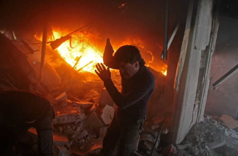 A Syrian man searches for people in a fire following regime air strikes on the rebel-held town of Douma on February 7, 2018