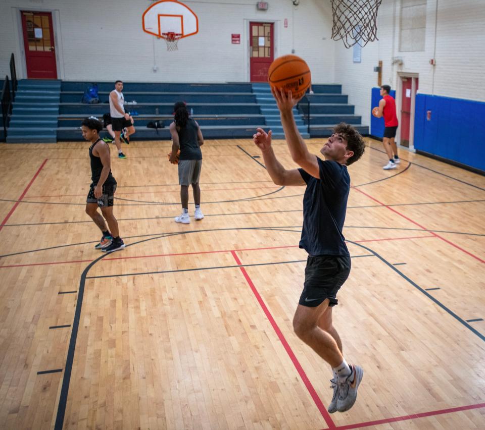 Noah Beaudet and other players warm up before a pickup basketball league game at Mills Town Hall.