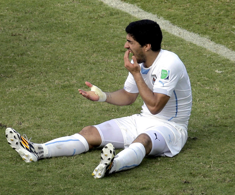 FILE - Uruguay's Luis Suarez holds his teeth after running into Italy's Giorgio Chiellini's shoulder during the group D World Cup soccer match between Italy and Uruguay at the Arena das Dunas in Natal, Brazil, Tuesday, June 24, 2014. (AP Photo/Hassan Ammar, File)