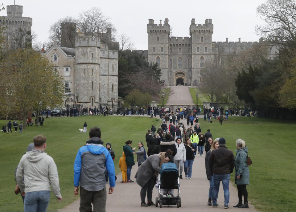 People stroll on The Long Walk towards Windsor Castle in Windsor, England, Saturday, April 10, 2021. Britain's Prince Philip, the irascible and tough-minded husband of Queen Elizabeth II who spent more than seven decades supporting his wife in a role that mostly defined his life, died on Friday. (AP Photo/Frank Augstein)