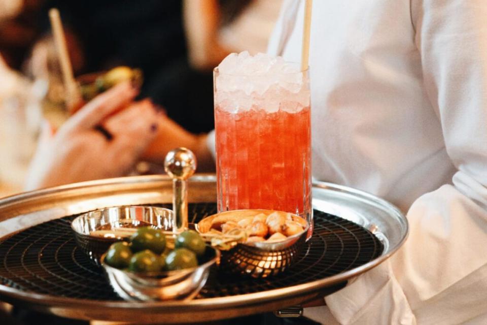 a waiter carrying a tray with a cocktail on it in sweden