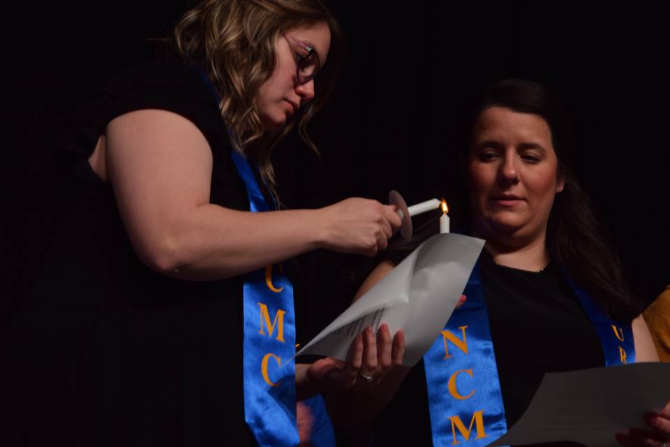 Nurse pinning graduates Codie Galer (left) and Adriana Gilroy (right) light candles during the 2023 Nurse Pinning ceremony. After all graduates had their candles lit, they said the international pledge for nurses.