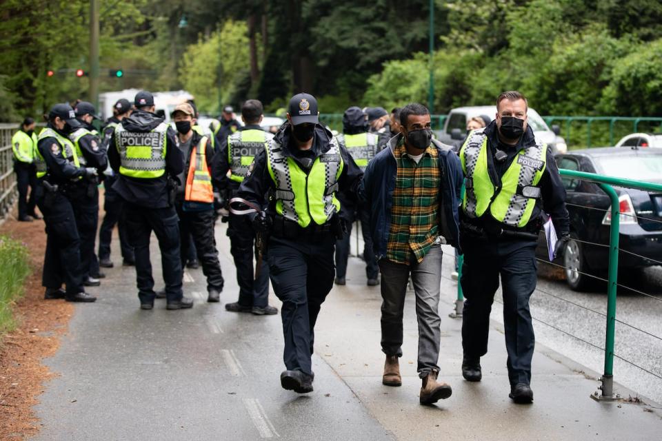 Zain Haq is arrested while blocking the sidewalk along Lions Gate Bridge Road in Vancouver, B.C., on Monday, May 3, 2021, as part of an Extinction Rebellion protest. 