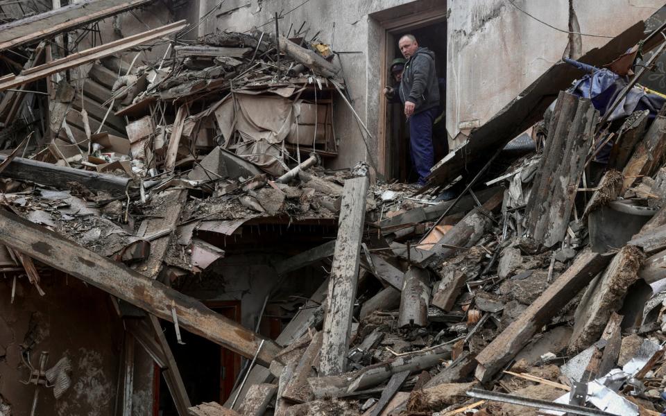 A local resident and a rescuer stand on debris of a building of local museum heavily damaged by a Russian missile strike, amid Russia's attack on Ukraine, in the town of Kupiansk, Kharkiv region - Viktoriia Yakymenko/REUTERS