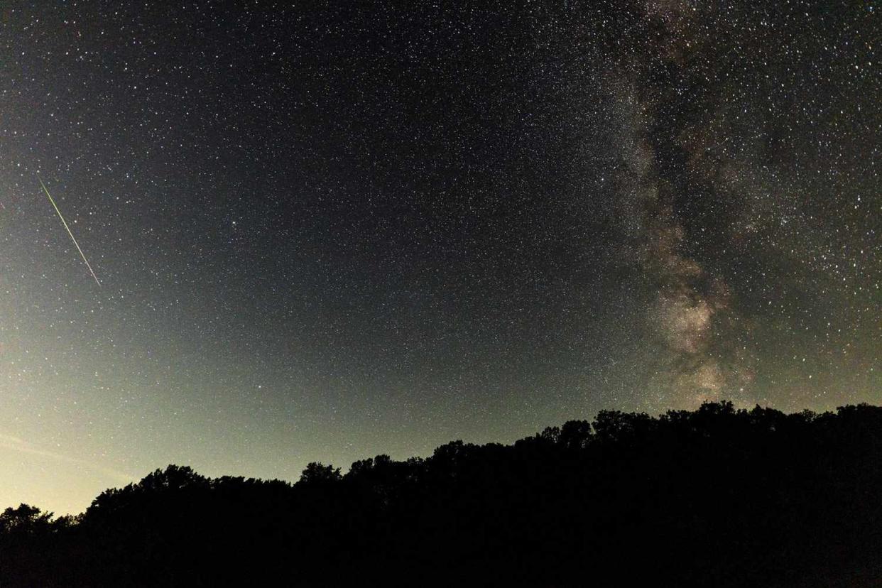 <p>Rick Kern/Getty</p> Meteor streaks across the sky during the Perseids meteor shower peak at Pedernales Falls State Park on August 12, 2024