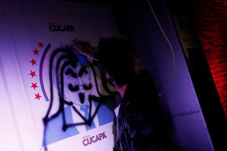 A reveler spray paints over an image of Republican presidential nominee Donald Trump during a Mexican brewery booze-up in Mexico City, Mexico, October 20, 2016. REUTERS/Carlos Jasso