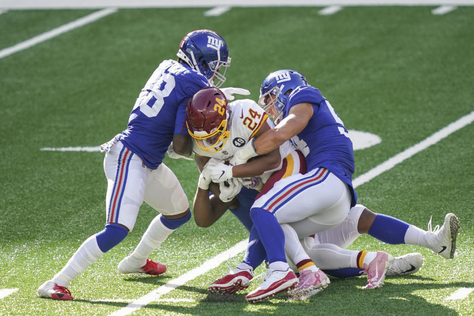 Washington Football Team running back Antonio Gibson (24) is tackled by New York Giants' Blake Martinez (54) and Montre Hartage (18) during the second half of an NFL football game Sunday, Oct. 18, 2020, in East Rutherford, N.J. (AP Photo/John Minchillo)