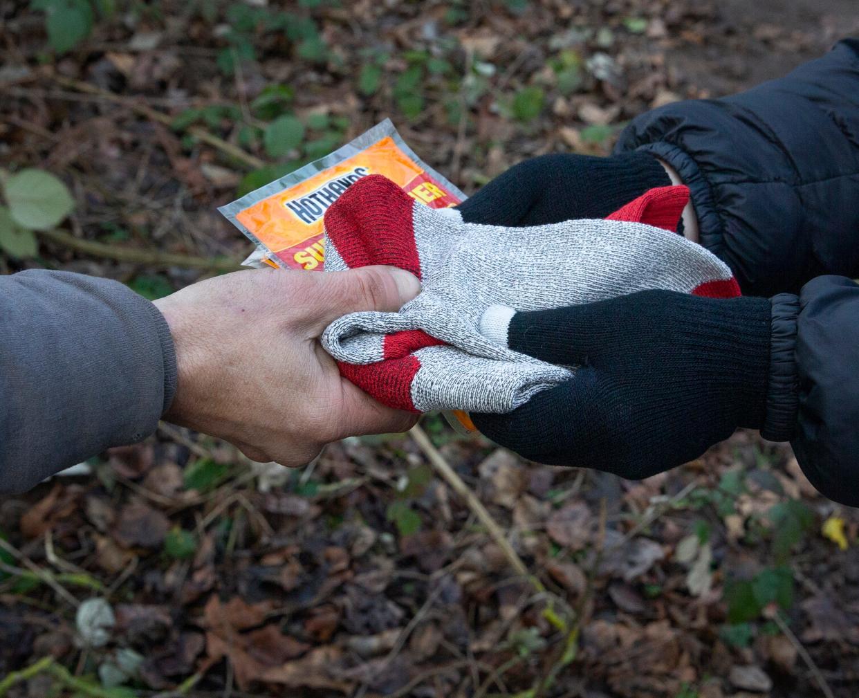 Lane County Outreach worker Theresa Burchell hands socks and hand warmer packets to a camper near the Mckenzie River last month during the Point In Time count of homeless people. Springfield city councilors are in discussions about changes to ordinances about sleeping on public property to comply with federal court rulings and a new state law.