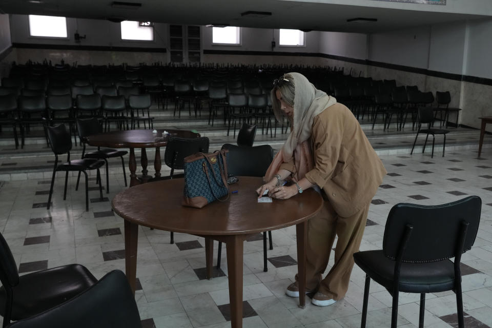 An Iranian woman fills out her ballot for the presidential runoff election at a polling station in Tehran, Iran, Friday, July 5, 2024. Iranians are voting in a runoff election to replace the late President Ebrahim Raisi, who was killed in a May helicopter crash in the country’s northwest along with the foreign minister and several other officials. (AP Photo/Vahid Salemi)