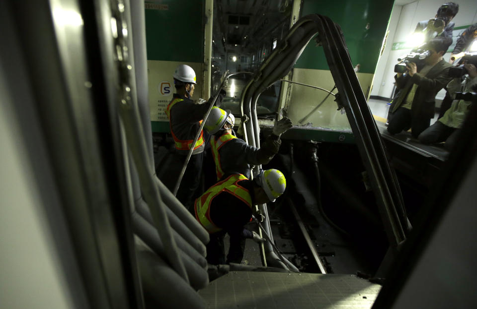 South Korea's subway workers try to repair a train after its collision at Sangwangshipri station in Seoul, South Korea, Friday, May 2, 2014. A subway train plowed into another train stopped at the station Friday, causing minor injuries for scores of people, a city official said. (AP Photo/Lee Jin-man)