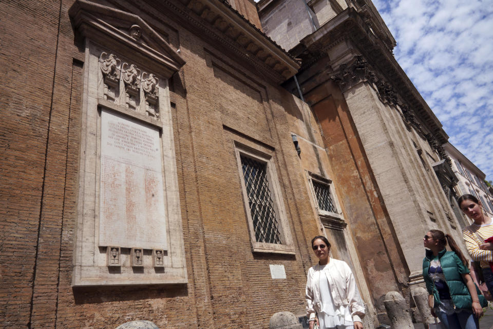 People walk past a plaque commemorating the fallen soldiers of WWI adorned with the original symbol of fascism, a bundle of sticks featuring an axe, carved along with eagles on the facade of the Madonna dei Monti church, in downtown Rome, Friday, May 3, 2019. While Germany systematically wiped out traces of Adolf Hitler’s Nazi regime after World War II, the legacy of his Axis ally, Benito Mussolini, remains present in Italy even today. (AP Photo/Andrew Medichini)