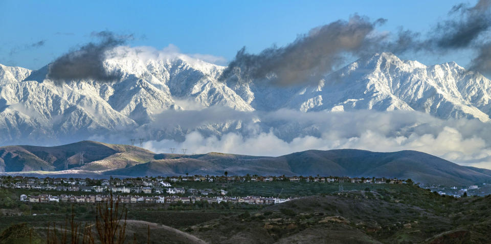 With a break in the cloud cover, the San Gabriel Mountains are covered in snow from the recent storms in an early morning view from the hills in eastern Orange, Calif., on Wednesday, Feb. 7, 2024. (Mark Rightmire/The Orange County Register via AP)