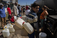 People line up at a tanker truck distributing drinking water amid the aftermath of Hurricane Ian in La Coloma, Pinar del Rio province, Cuba, Wednesday, Oct. 5, 2022. (AP Photo/Ramon Espinosa)