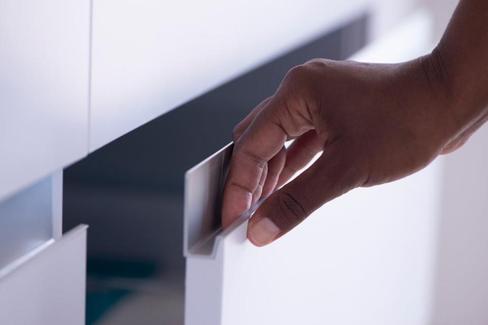 Woman pulling a drawer door aluminum handle.