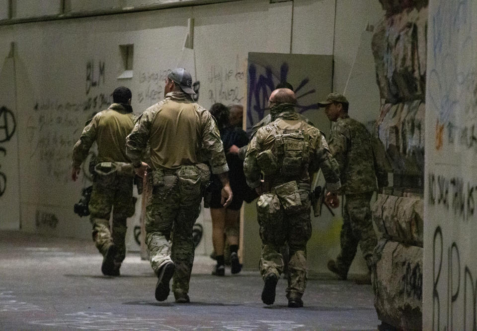 FILE - In this July 10, 2020, file photo, federal officers pull a protester into the Federal Courthouse, as protesters gather in downtown Portland, Ore. An Associated Press analysis of more than 200 arrests shows that even those accused of breaking the law during the nightly rallies don’t neatly fit into President Donald Trump’s depiction of protesters as “anarchists and agitators.” (Dave Killen/The Oregonian via AP)