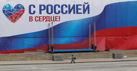 FILE PHOTO: A woman walks past a banner reading "With Russia in the heart!" ahead of the upcoming vote for a new leader of the self-proclaimed Luhansk People's Republic (LNR), in Luhansk, Ukraine November 9, 2018. REUTERS/Alexander Ermochenko