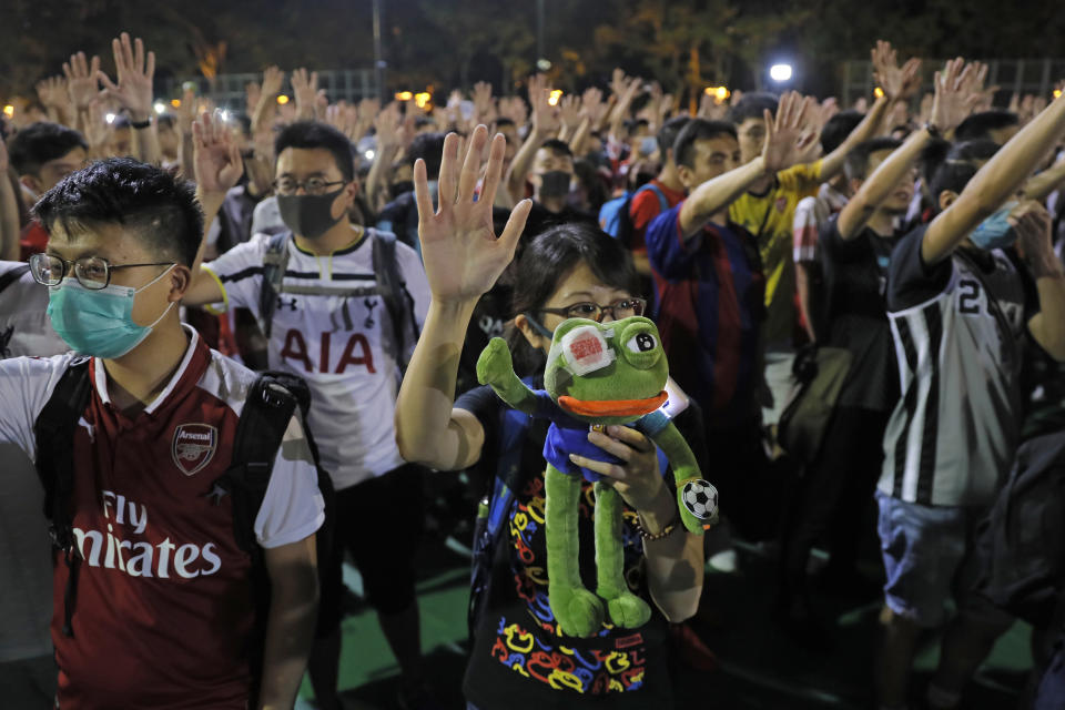A pro-democracy football fan shows a frog toy as she forms part of a human chain at Victoria Park in Hong Kong, Wednesday, Sept. 18, 2019. An annual fireworks display in Hong Kong marking China's National Day on Oct. 1 was called off Wednesday as pro-democracy protests show no sign of ending. (AP Photo/Kin Cheung)