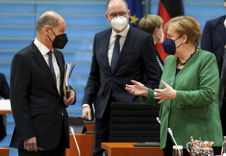 German Finance Minister Olaf Scholz, left, and German Chancellor Angela Merkel, right, talk as they arrive for the weekly cabinet meeting at the Chancellery in Berlin, Germany, Wednesday, May 12, 2021. (AP Photo/Michael Sohn)