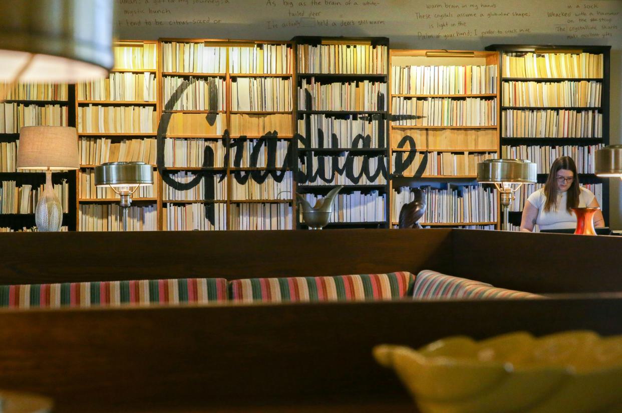 A bookshelf decorates the reception desk of The Graduate hotel Friday, April 12, 2024 in downtown Iowa City, Iowa. The boutique hotel is being bought by Hilton.