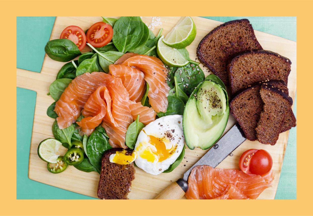 Why the Nordic Diet Is Suddenly Everywhere , Healthy snack with salted salmon, spinach, avocado, tomato, toasted rye bread and poached egg. Making delicious salad with fresh vegetables on cutting board viewed from above, time to snack, favorite meal