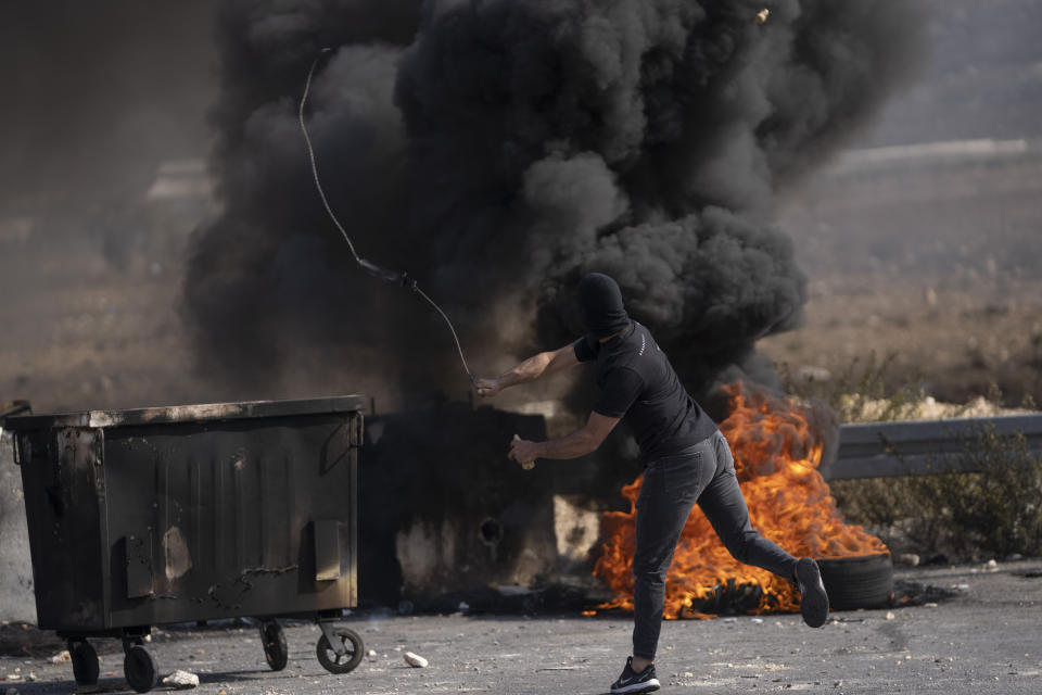 A Palestinian protester uses a slingshot during clashes with Israeli army troops in the West Bank city of Ramallah, Thursday, Oct. 20, 2022. Palestinians launched a general strike on Thursday throughout the West Bank and east Jerusalem in response to the death of a suspected Palestinian attacker. (AP Photo/Nasser Nasser)