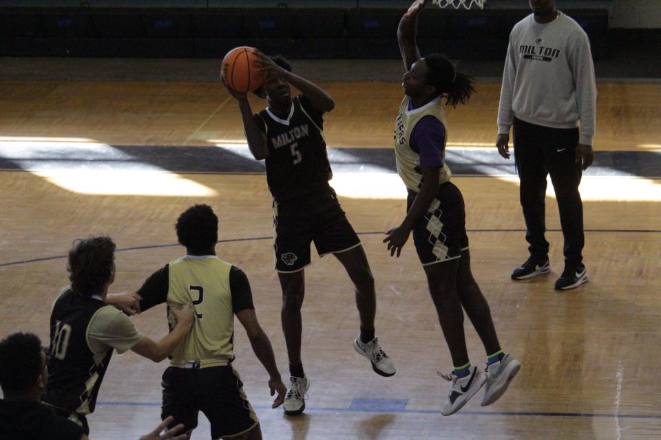 Milton's Jackson Gee (5) looks to shoot the ball over a couple defenders during the Panthers' boys basketball team's practice on Monday, Dec. 18, 2023.