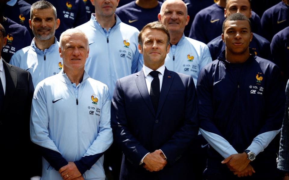 French President Emmanuel Macron (C) stands next to French head coach Didier Deschamps (L) and French forward Kylian Mbappe (R) as they pose for a group photo