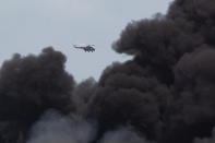 A helicopter flies over the Matanzas Supertanker Base, as firefighters and specialists work to quell the blaze which began during a thunderstorm in Matanzas, Cuba, Monday, Aug. 8, 2022. Cuban authorities say lightning struck a crude oil storage tank at the base, sparking a fire that sparked four explosions. (AP Photo/Ismael Francisco)