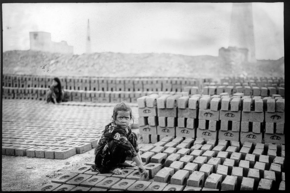 Marwan, 7, scoops out a chunk of mud with his hands, kneading it until it's pliable enough to put into a mold, in a brick factory on the outskirts of Kabul, Afghanistan, Tuesday, May 30, 2023. (AP Photo/Rodrigo Abd)