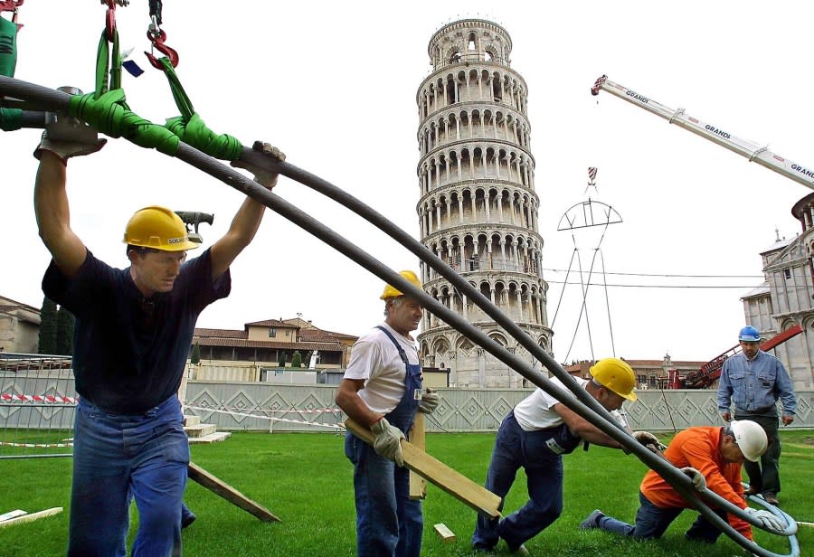 Construction workers remove steel cables known as “suspenders” from the base Leaning Tower of Pisa, central Italy, Tuesday, May 15, 2001, which had been placed in 1998 to support the tower during reinforcement excavations. Four cables -100 meters long and weighing 4 tons each -, had been placed to balance the tower during excavation in case of a possible collapse. The tower is expected to open to the public in November 2001. (AP Photo/Fabio Muzzi)