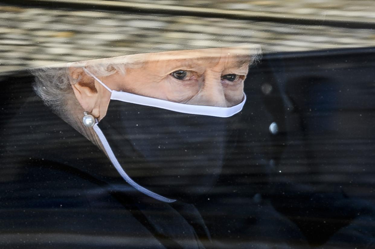 Britain's Queen Elizabeth II follows the coffin in a car as it makes it's way past the Round Tower during the funeral of Britain's Prince Philip inside Windsor Castle in Windsor, England Saturday April 17, 2021.