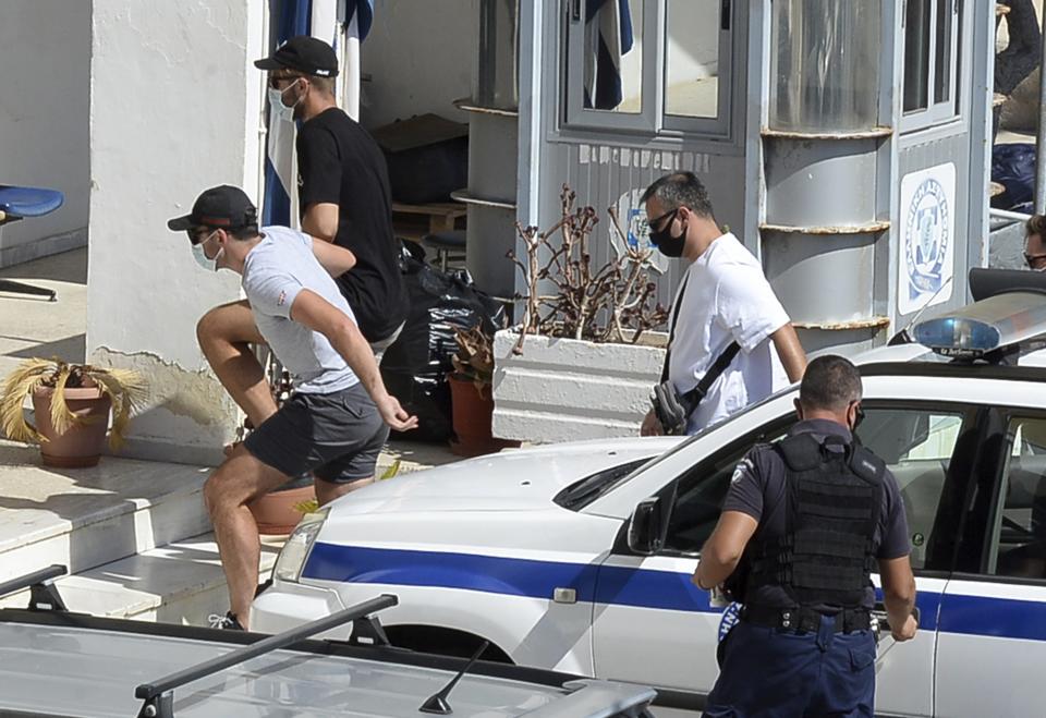 Manchester United captain Harry Maguire, left, is escorted by plain clothed police officers as he arrives at the police station on the Aegean island of Syros, Greece, on Friday. (Giorgos Solaris/InTime News via AP)