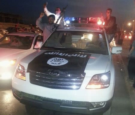 Fighters of the Islamic State of Iraq and the Levant (ISIL) celebrate on a police vehicle along a street in the city of Mosul, June 23, 2014. REUTERS/Stringer