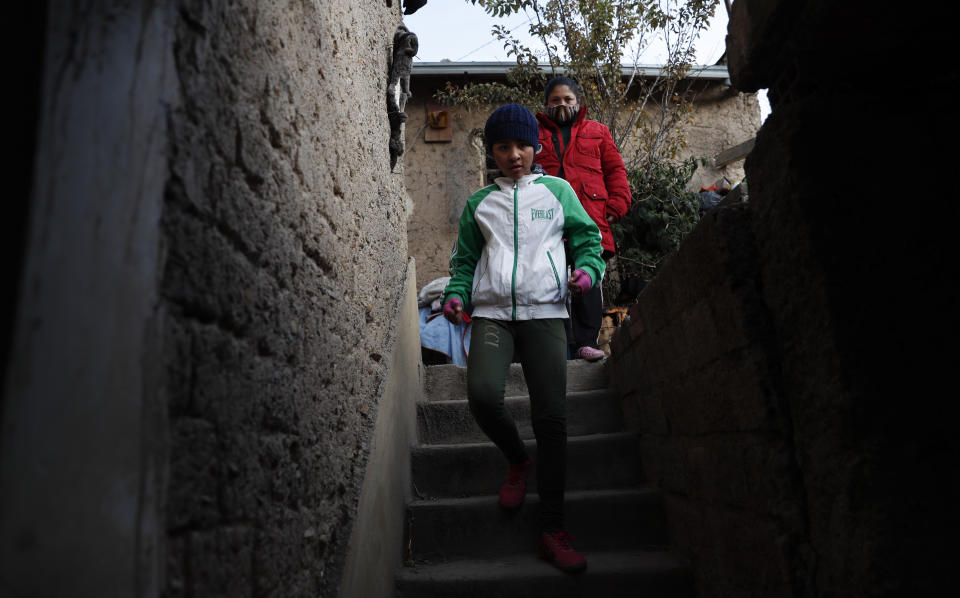 Gracce Kelly Flores, a 12-year-old boxer who goes by the nickname Hands of Stone, leaves home under the watch of her mother for a run as part of her daily boxing workout in Palca, Bolivia, early Thursday, June 10, 2021, amid the COVID-19 pandemic. At age 8, Flores defeated a 10-year-old boy, and with three national boxing medals under her belt, she dreams of reaching the women's boxing world championship. (AP Photo/Juan Karita)