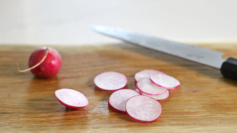 Thinly sliced radish on a wooden cutting board